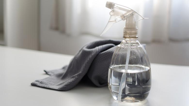 white vinegar inside a spray bottle next to a towel on a countertop