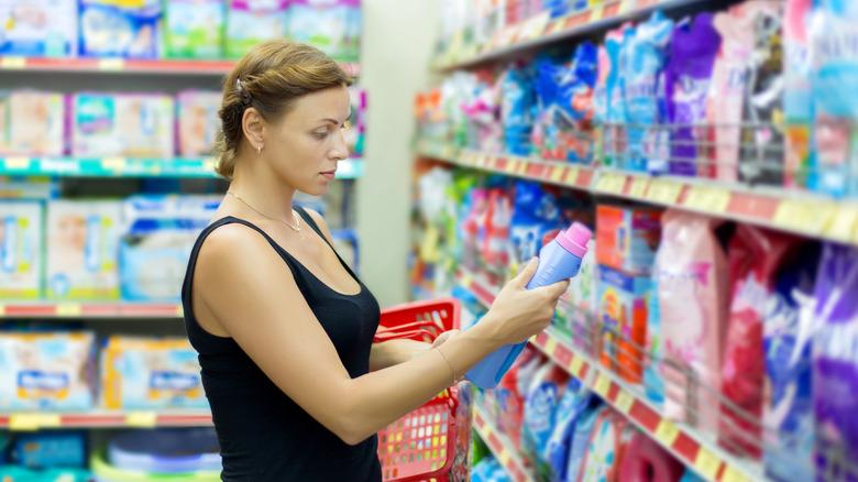 Woman taking laundry product from store shelf