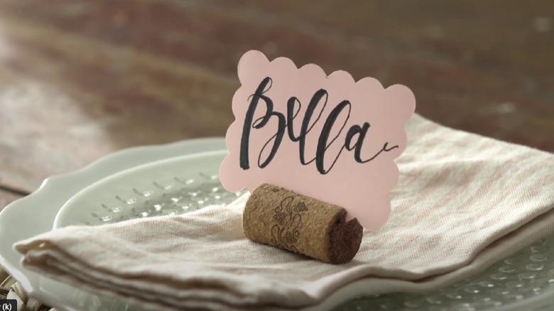 A dinner setting with a place card holder made from a cork.