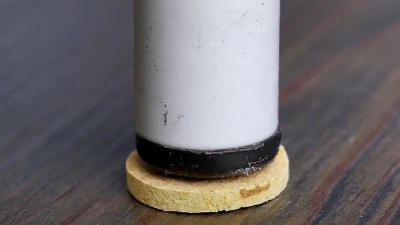 The end of a furniture leg sitting on top of a slice of cork off the floor.