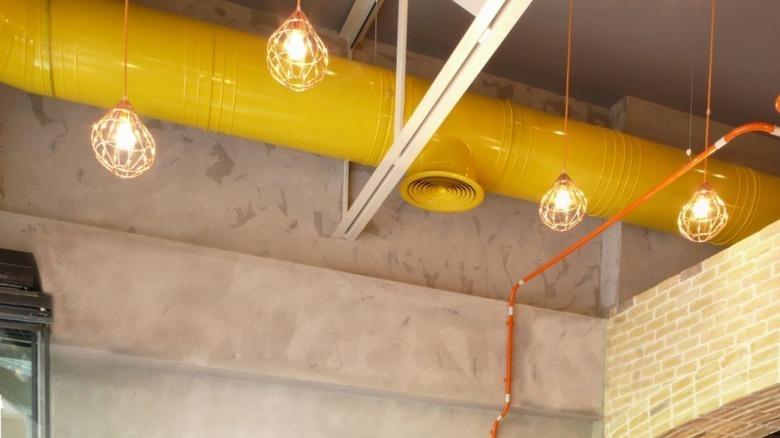 Urban living room with yellow painted pipe in ceiling