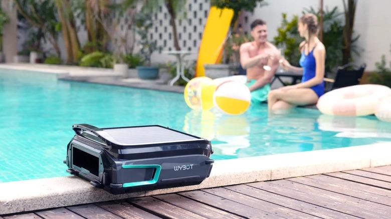 wybot f1 on the side of a pool with a happy couple in the background