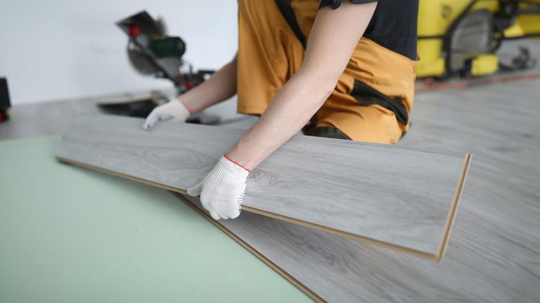 Person placing gray laminate boards on floor