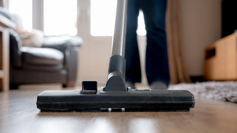 Person pushing a vacuum cleaner on laminate floor