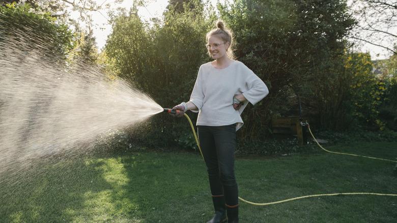 A woman watering her lawn with a hose.