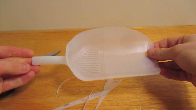 Hands holding a small milk jug scoop over a table