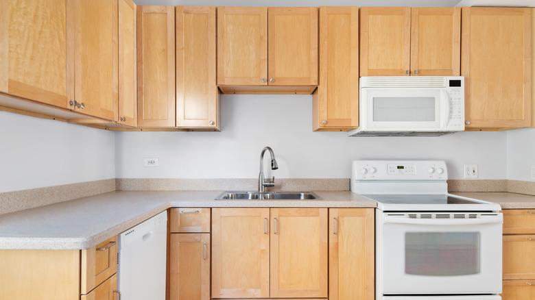 Dated kitchen with oak cabinetry and white appliances