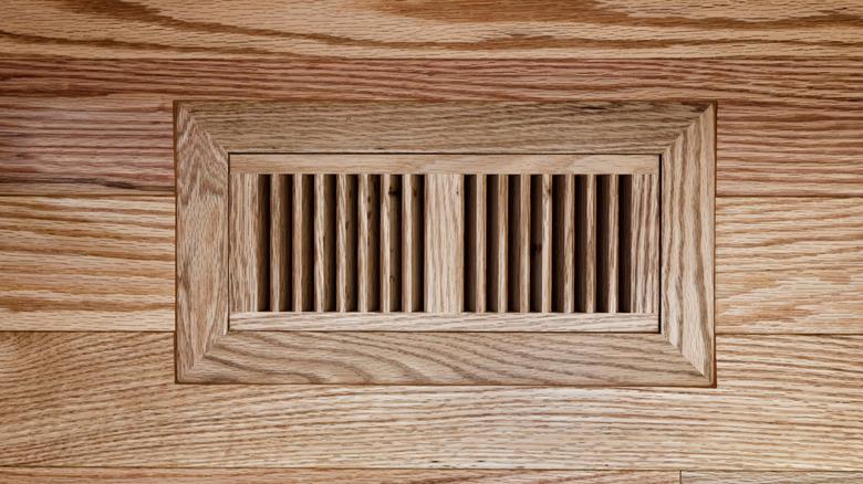 medium-toned wood floor with a matching wood floor vent cover for HVAC system