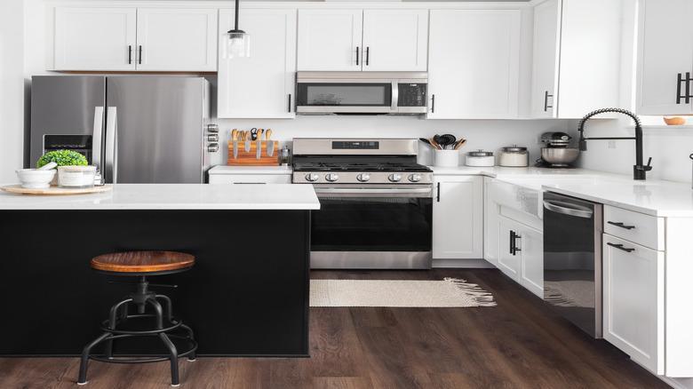 white kitchen with stainless steel appliances and gap between cabinet and ceiling
