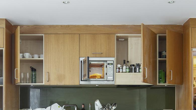 wooden cabinets in kitchen that reach to the ceiling and have some doors open