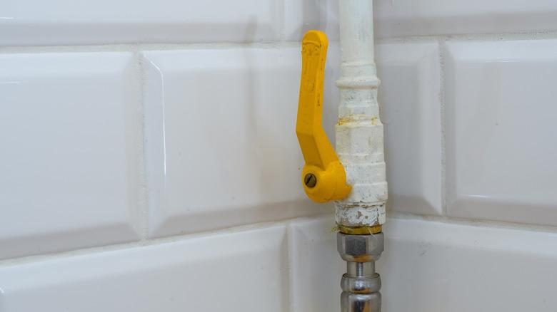 Open yellow gas line valve mounted to a wall