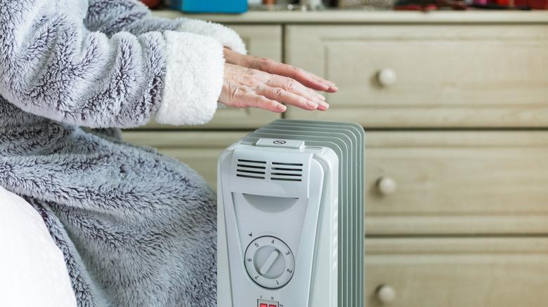 Woman holding her hands over an electric space heater