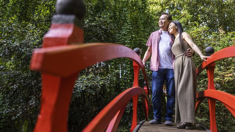 Man and woman taking in a Japanese garden from a bridge