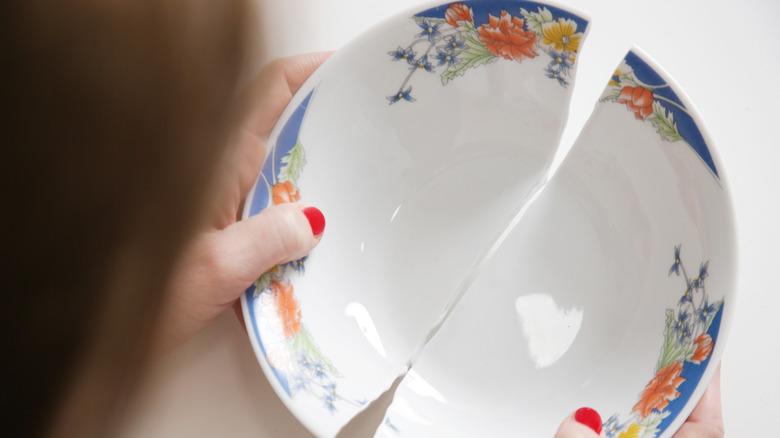 woman with red fingernails holding broken ceramic bowl