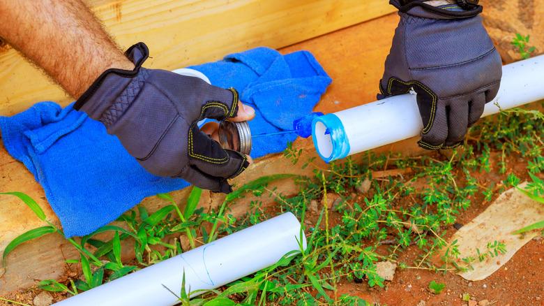 contractor hands placing metal cap plastic pipe